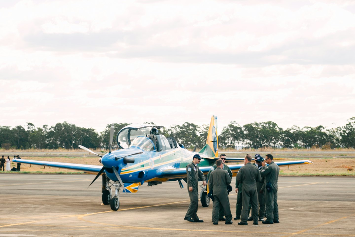 Zwei Piloten in Fliegeranzügen besprechen ein Propeller-Trainingsflugzeug auf dem Rollfeld.